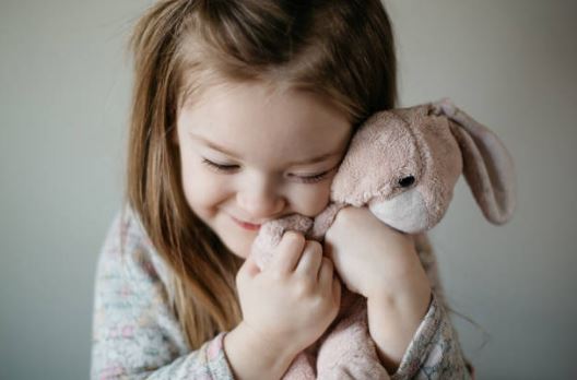 Petite fille qui câline son doudou lapin