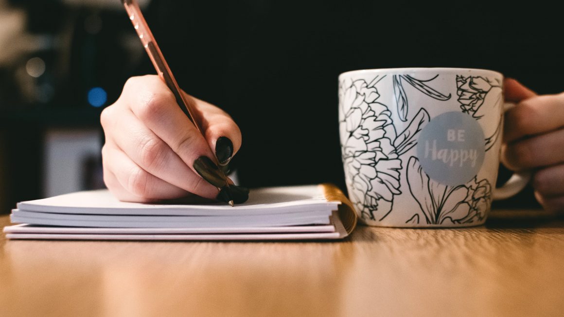 Jeune femme qui écrit dans un carnet pour être heureuse