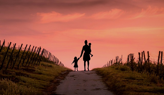 mère avec ses enfants au bout d'un chemin avec couchée de soleil